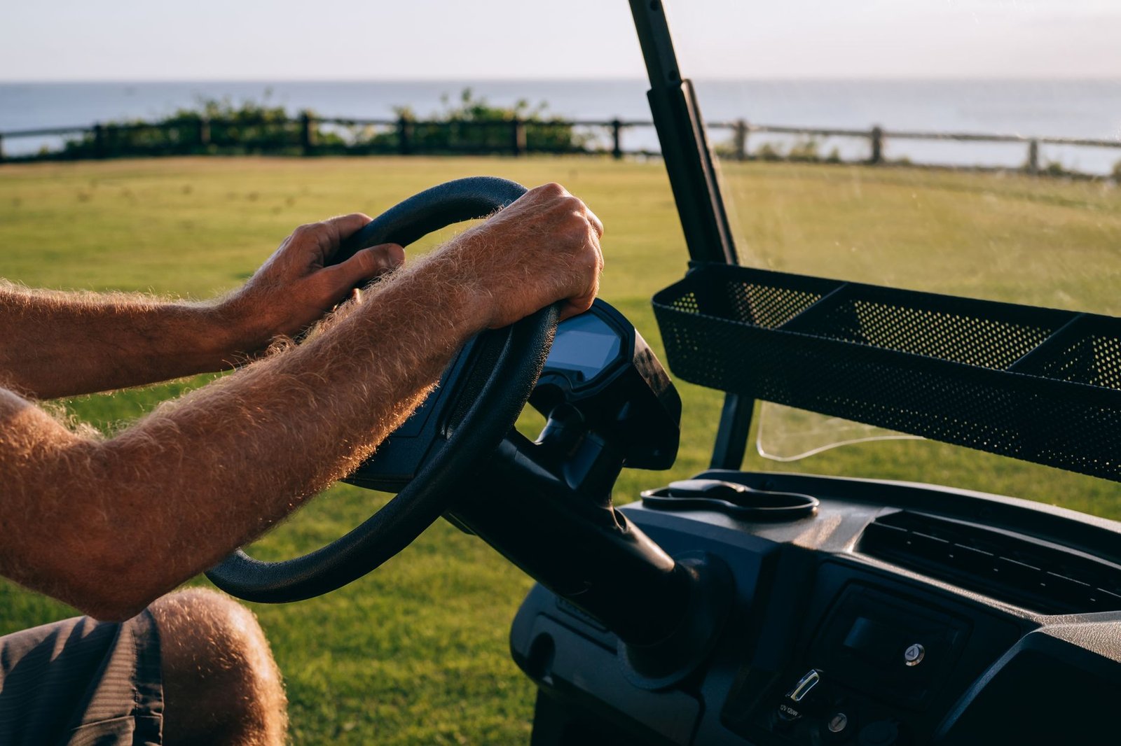 Close-up of hands on a golf cart's steering wheel