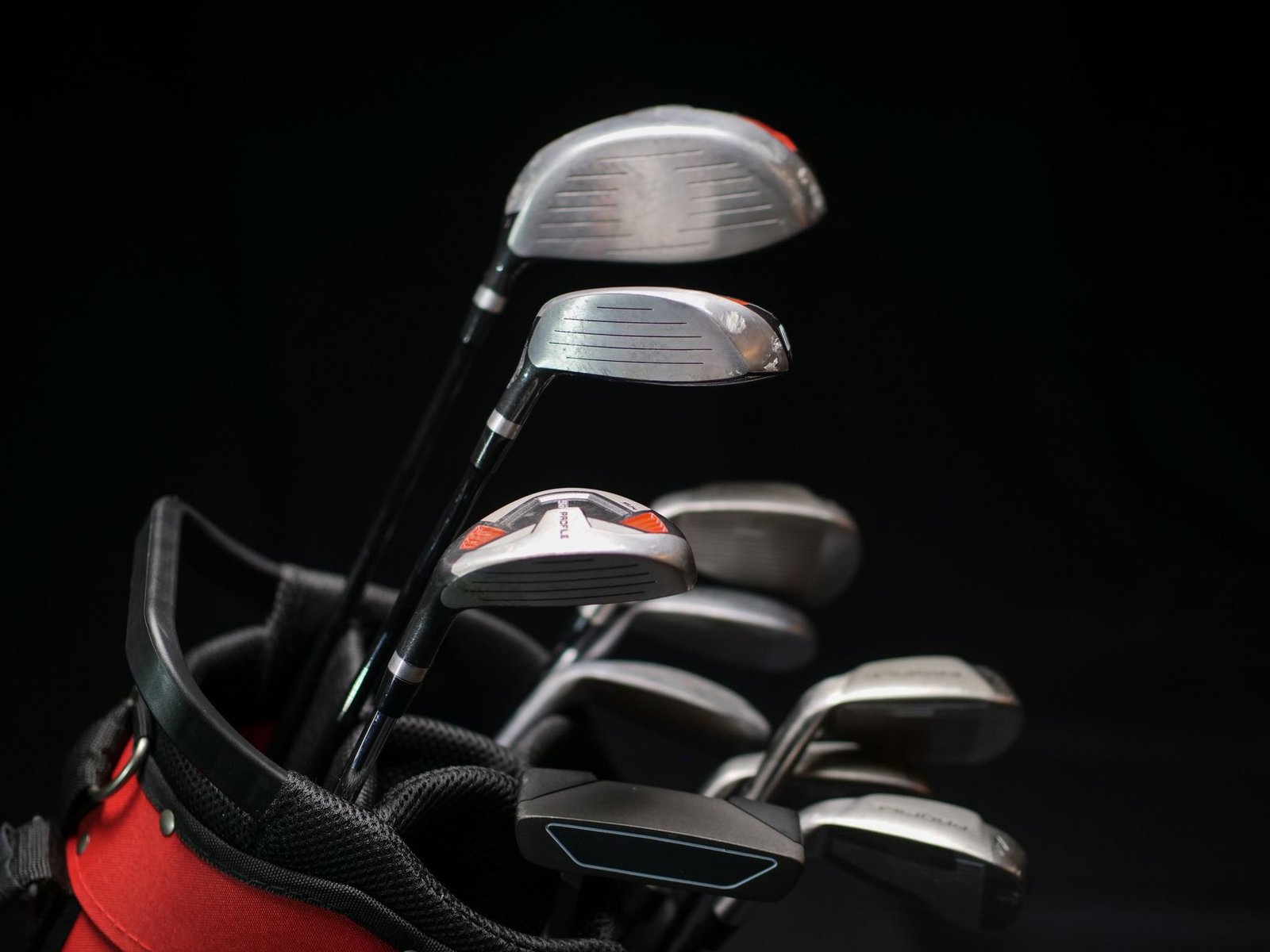 Close-up of a full golf club set including irons, driver, and putter showing different swing weight builds
