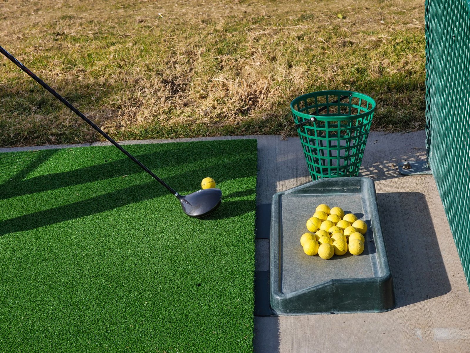 Golf driving range setup with club and balls, used for tracking swing speed progress over time