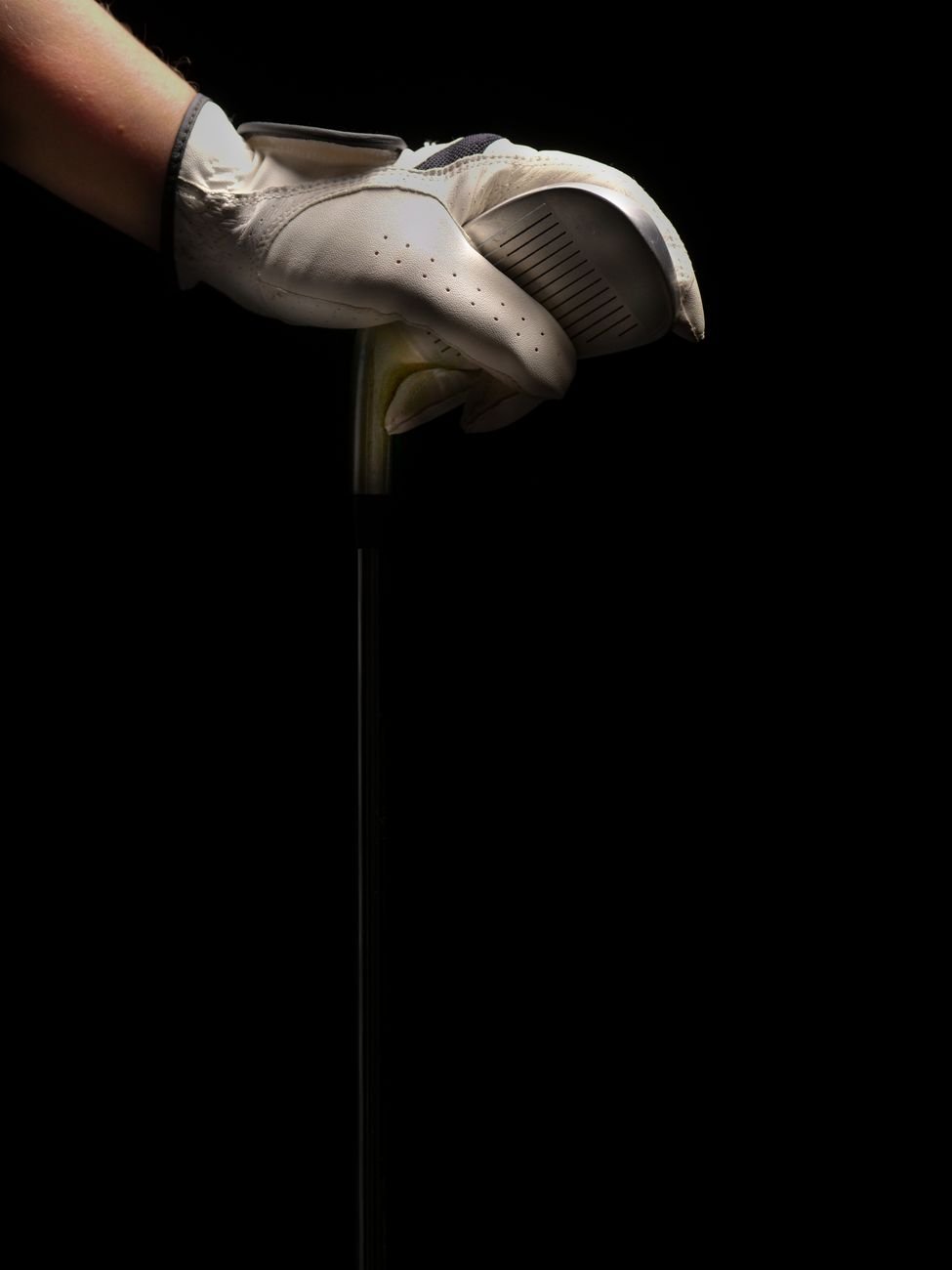 gloved hand gripping a golf club to test how grip size affects ball flight