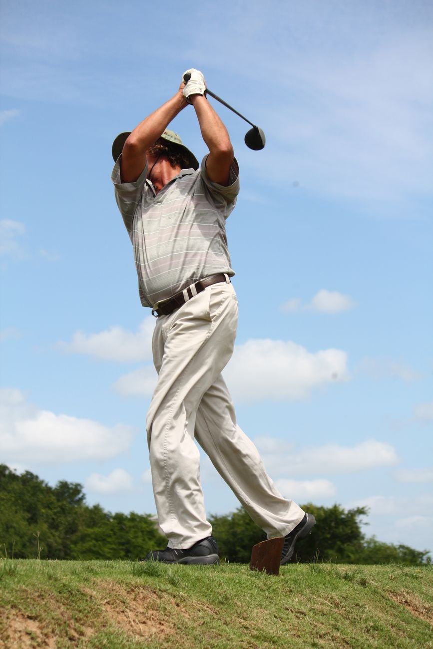 Golfer at full extension in the follow-through, the position that loads the lead shoulder most