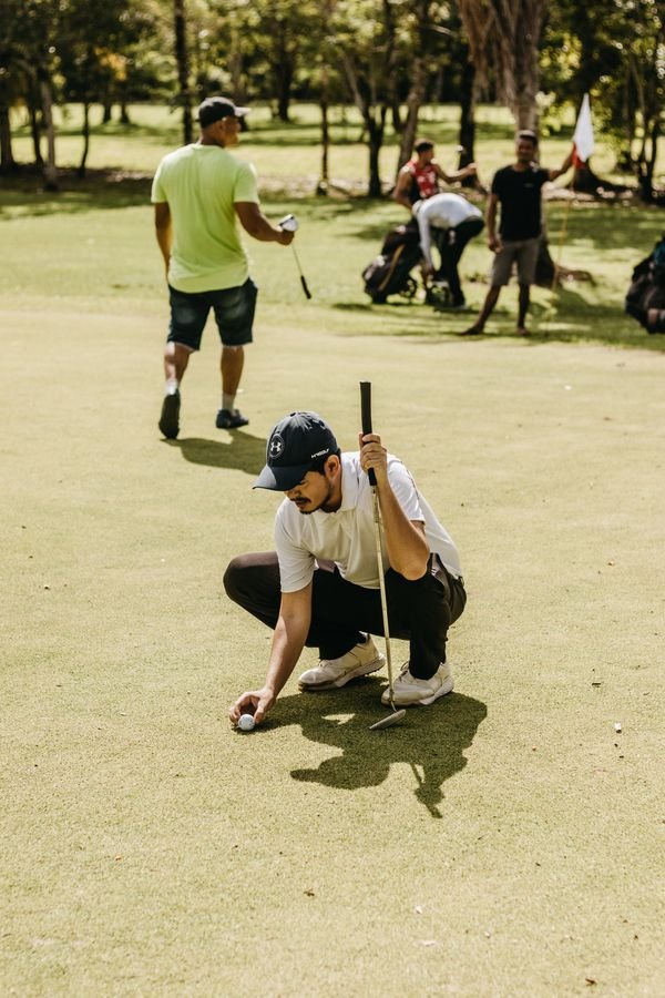 Golfer crouching down to line up a putt on the green