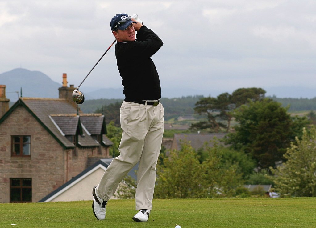 Golfer playing an iron shot on a links-style course