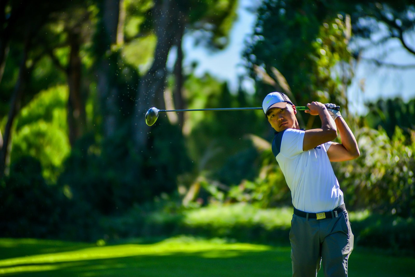 Golfer executing a powerful downswing on a golf course, demonstrating the sequencing that adds clubhead speed