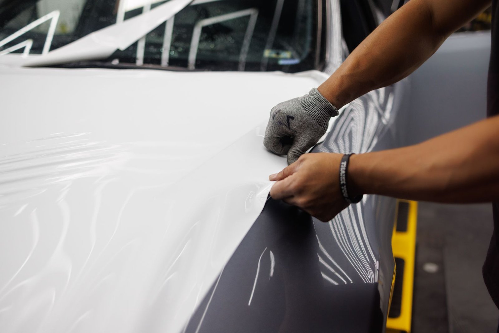 Close-up of a vinyl wrap film being applied with a squeegee, the same technique used for golf cart wraps