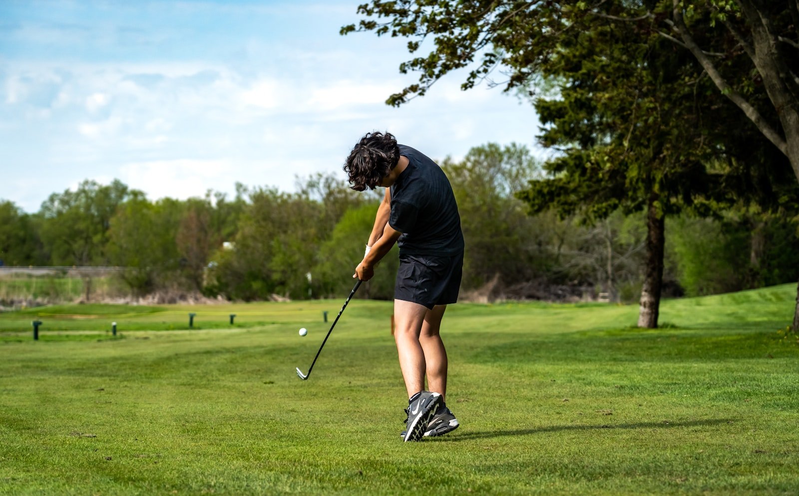 Golfer swinging through impact — the same motion the best hybrid golf clubs for seniors are designed to make easier