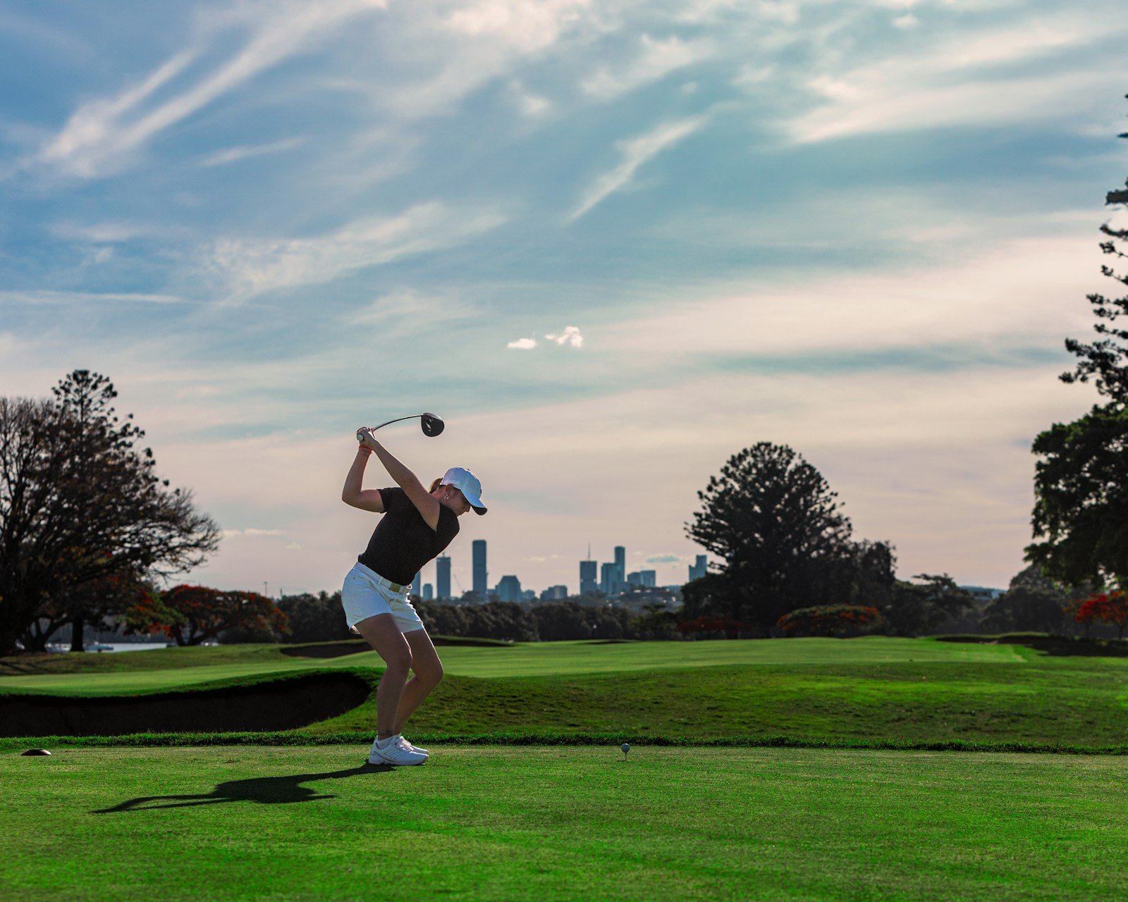 Golfer swinging a club on a green fairway
