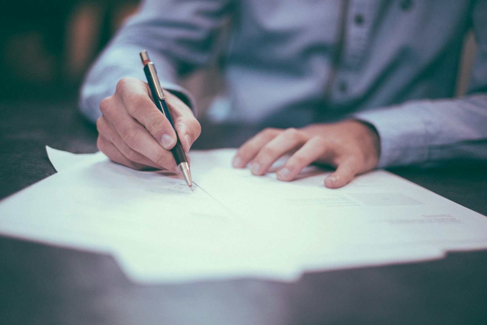 Person signing a document at a desk, representing the registration and insurance paperwork required for a street-legal golf cart