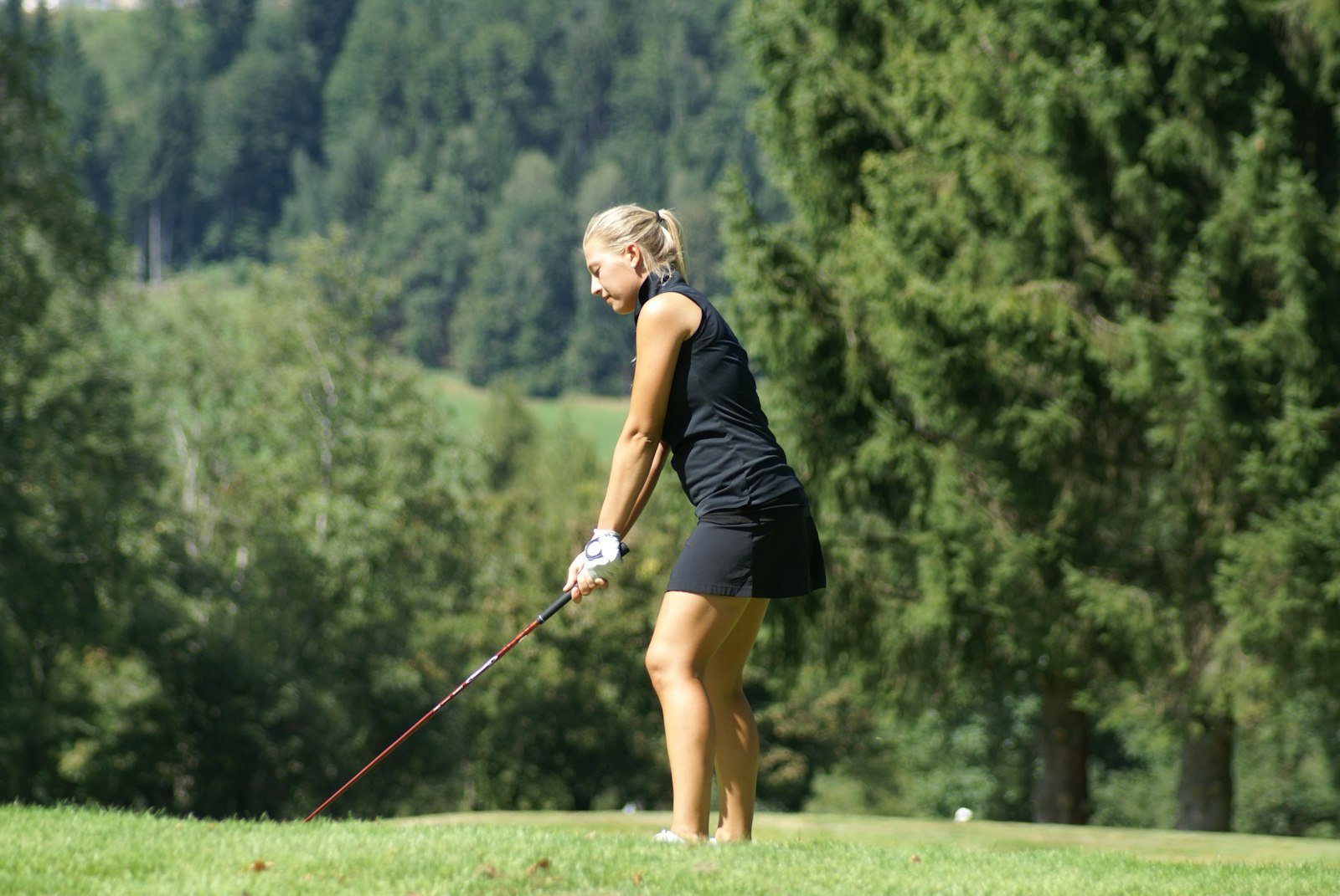 A woman golfer at address with standard-length clubs on the course