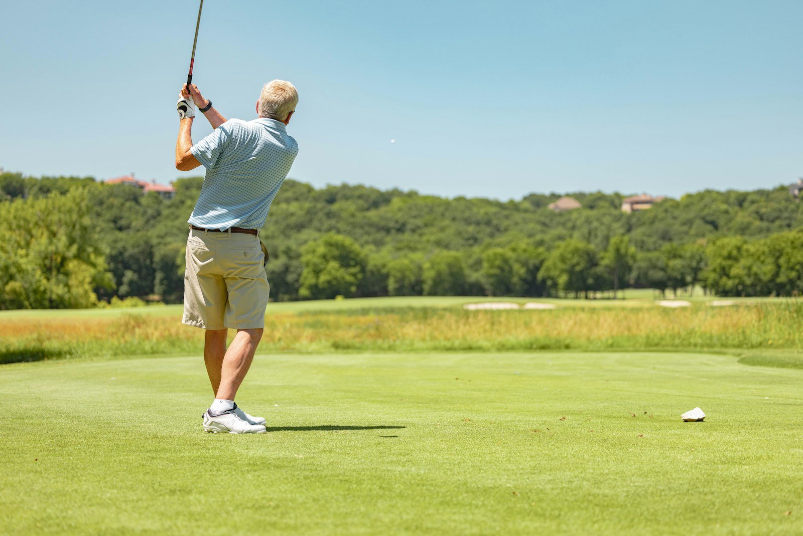 Golfer completing a full swing follow-through on the course
