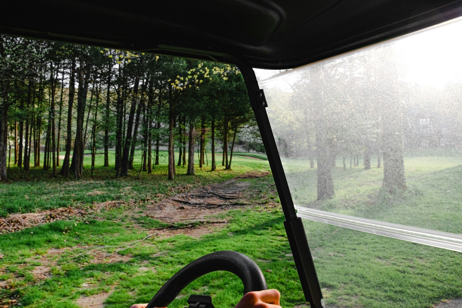 View through a hazy, weathered golf cart windshield showing why regular cleaning matters