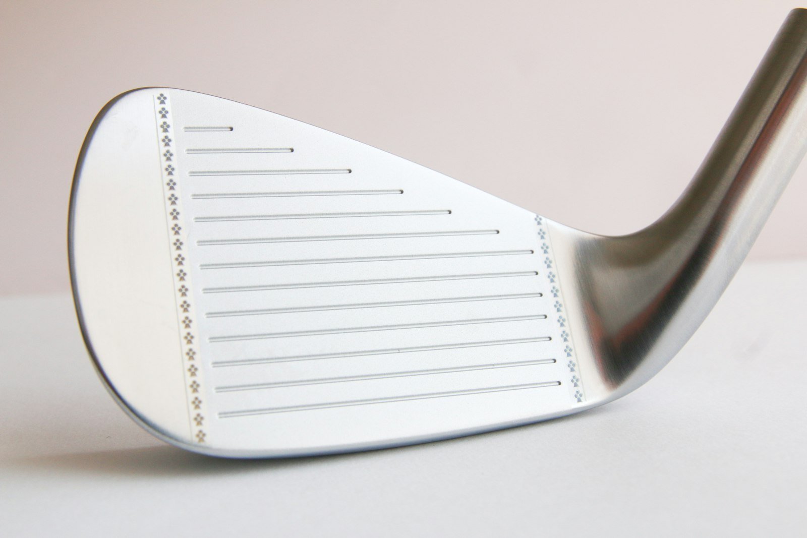 Close-up of a game-improvement iron clubface showing wide grooves and perimeter weighting