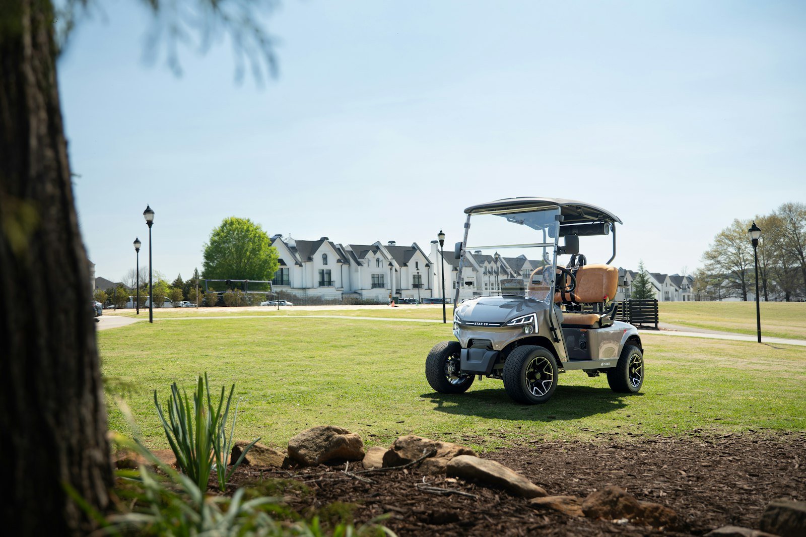 Modern golf cart with a clear golf cart windshield installed, parked on a resort lawn