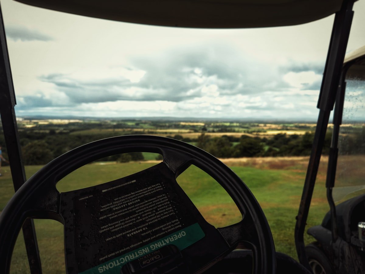 The steering wheel and roof struts of a golf cart, common places to mount a golf cart fan