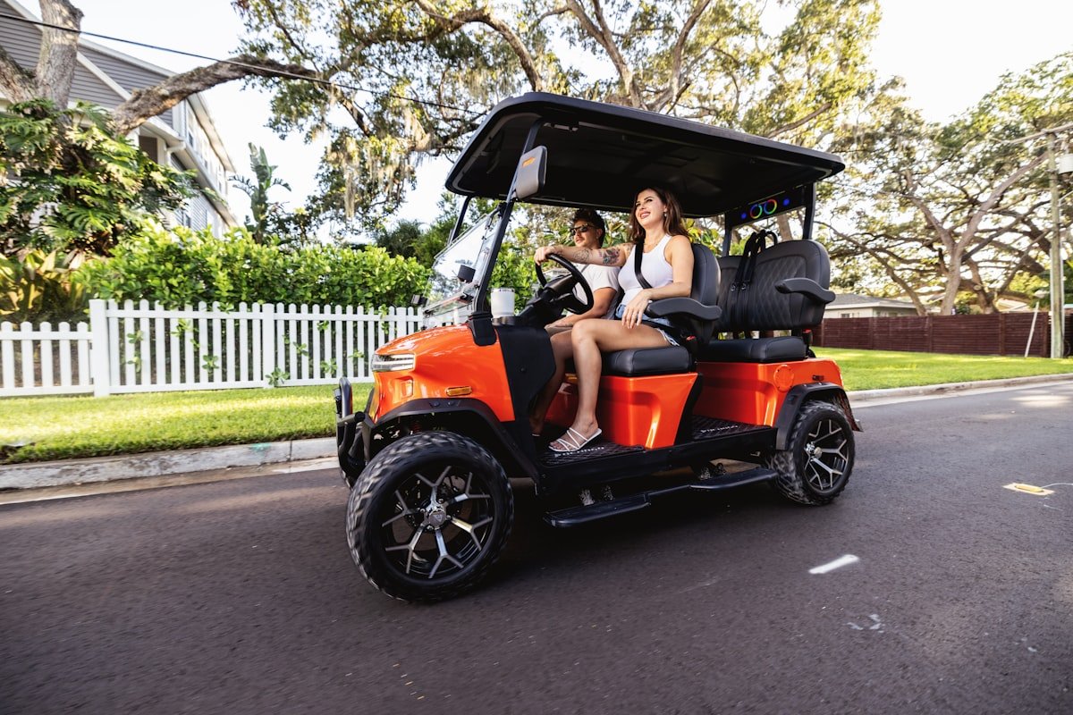 Two passengers riding a golf cart on a hot, sunny day