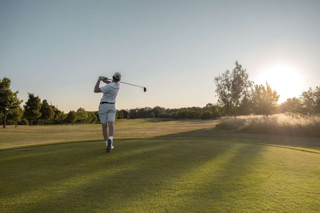 A golfer driving a ball off the tee at sunset, where compression and swing speed meet