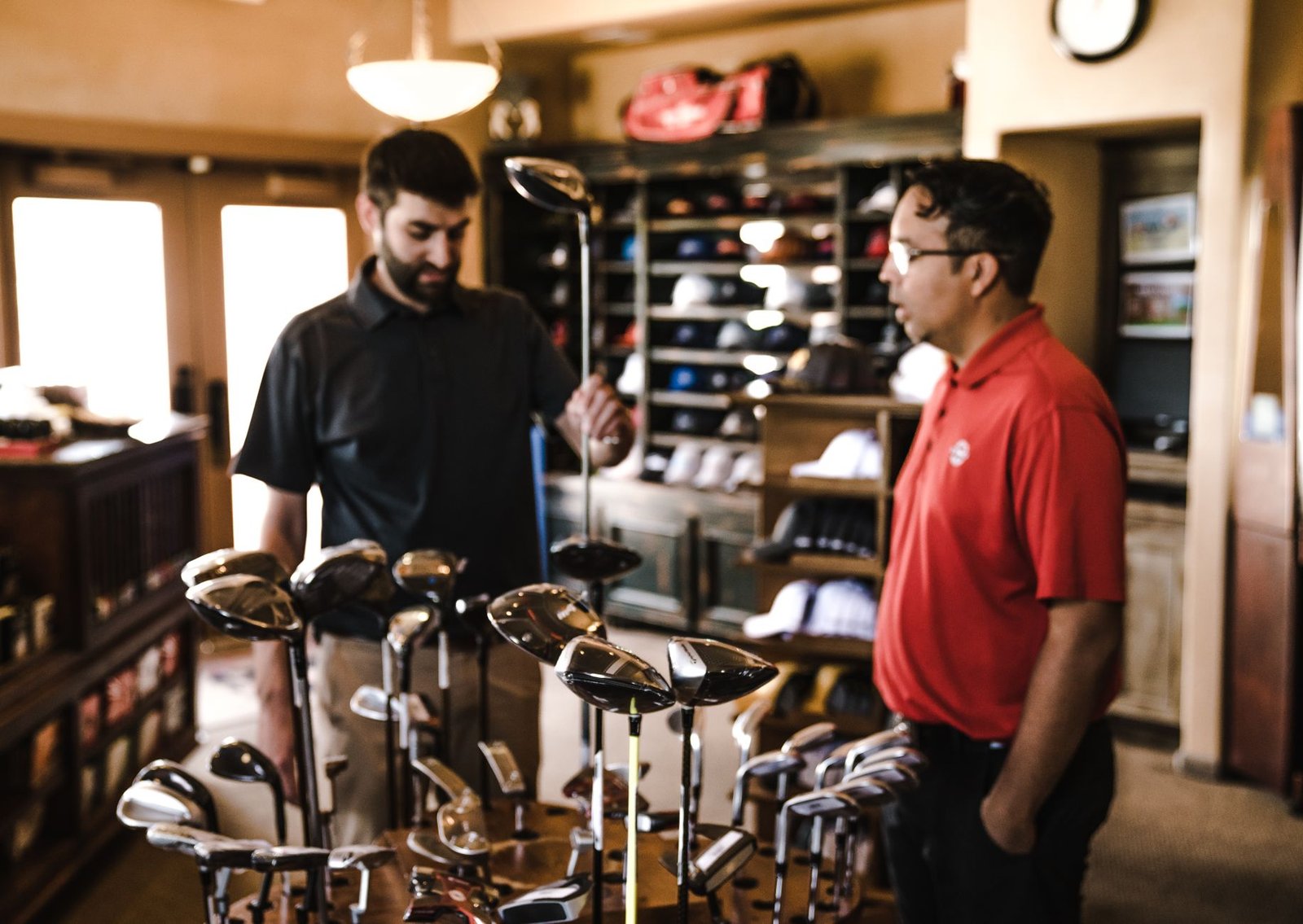 Two golfers browsing a rack of clubs at a sporting goods store