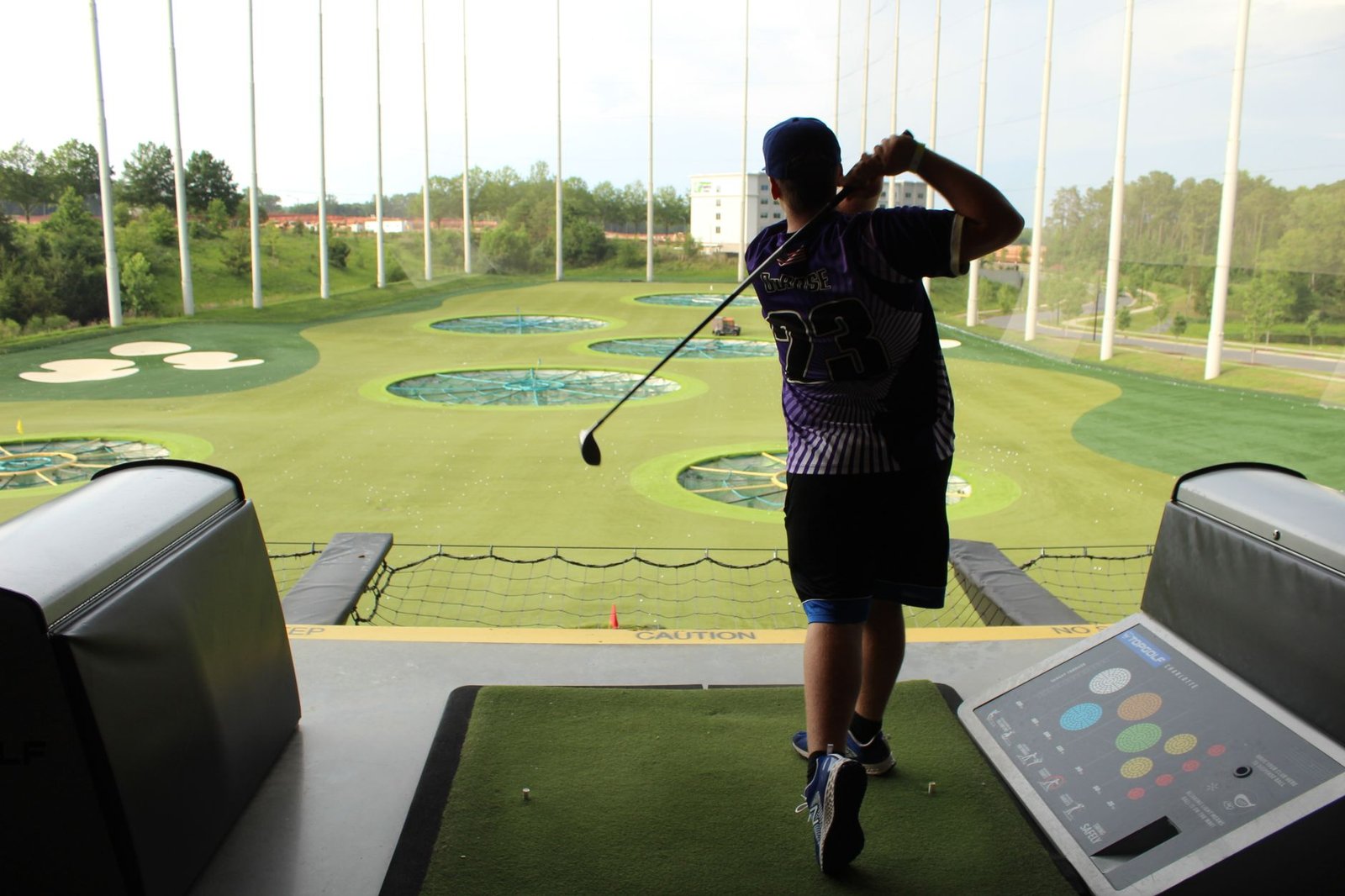 Golfer practising at a driving range where swing speed is commonly measured