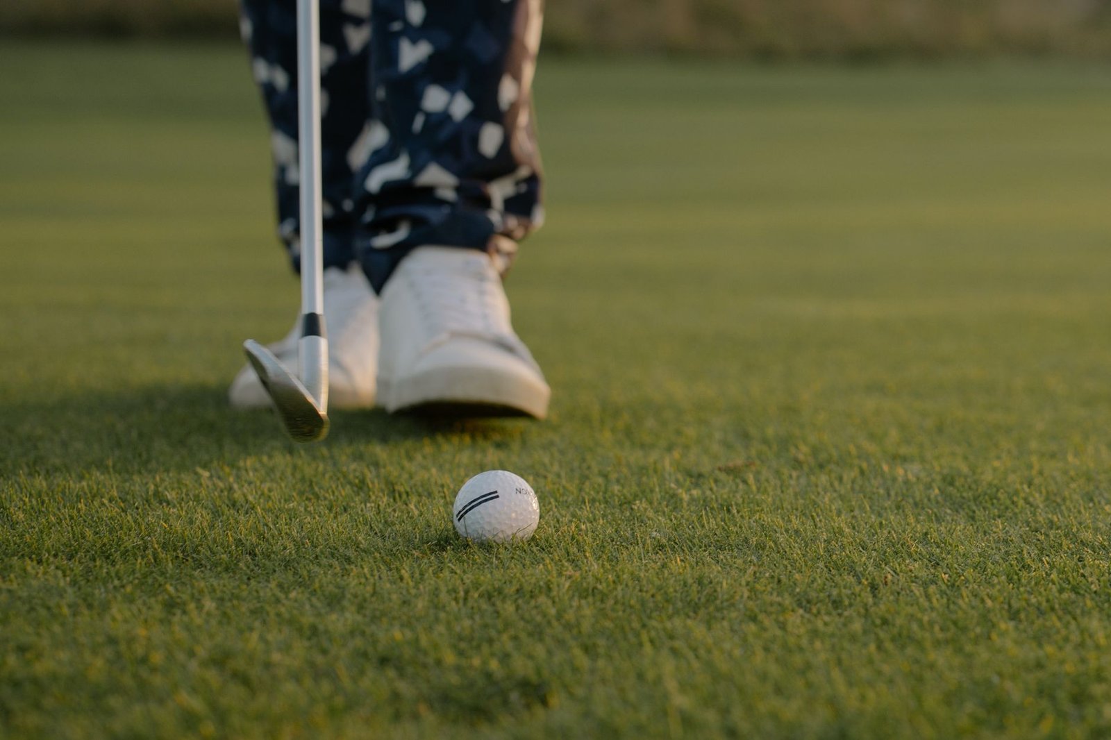 Golfer addressing a putt with feet set and putter behind the ball on the green