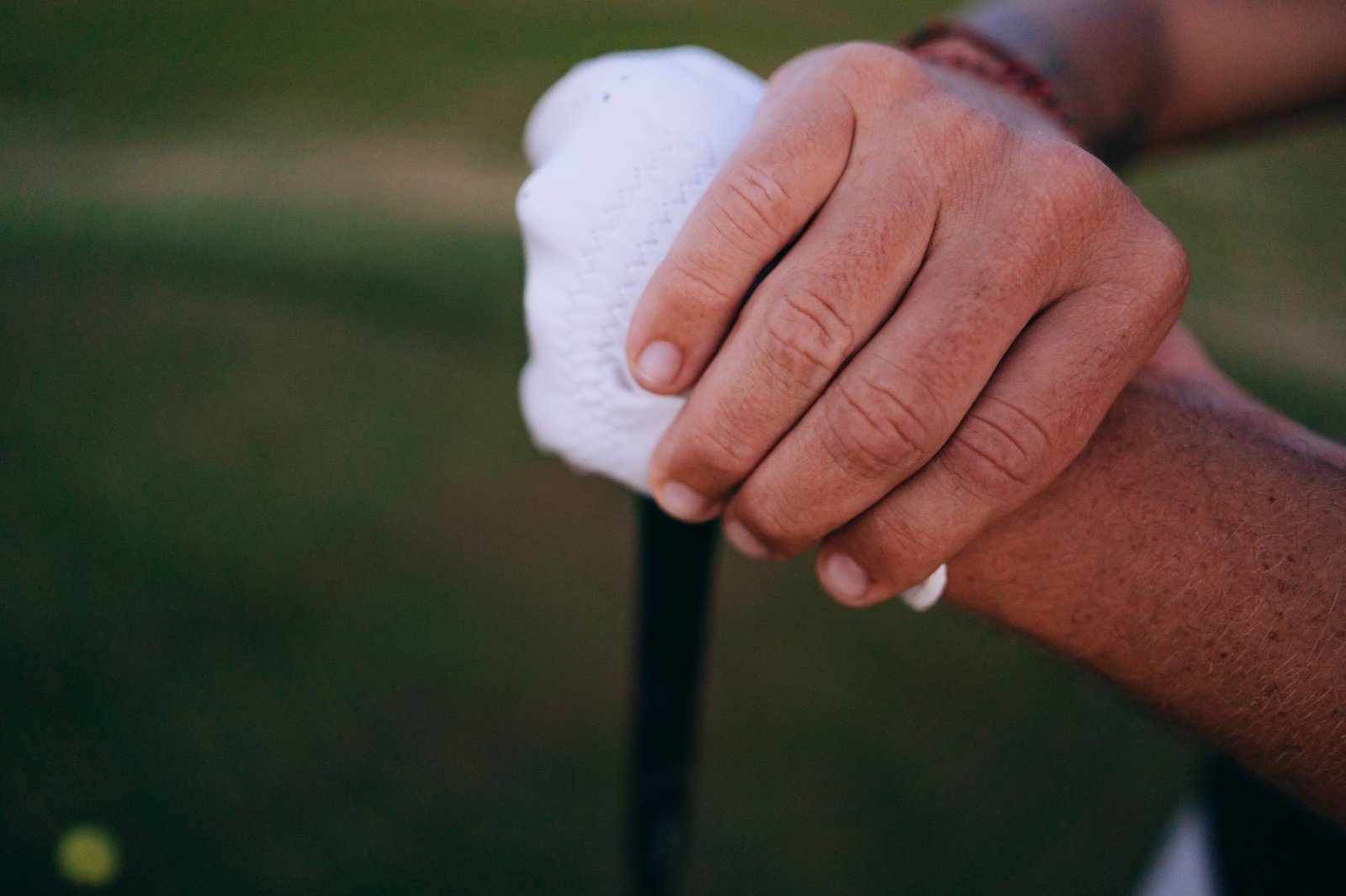 Close-up of gloved hands demonstrating a reverse overlap putting grip on the club