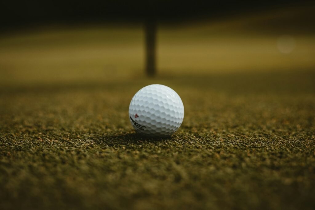 Selective focus photo of a single white golf ball on grass