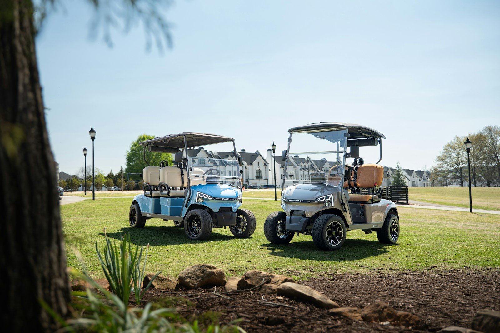 Two electric golf carts parked side by side on a sunny green lawn