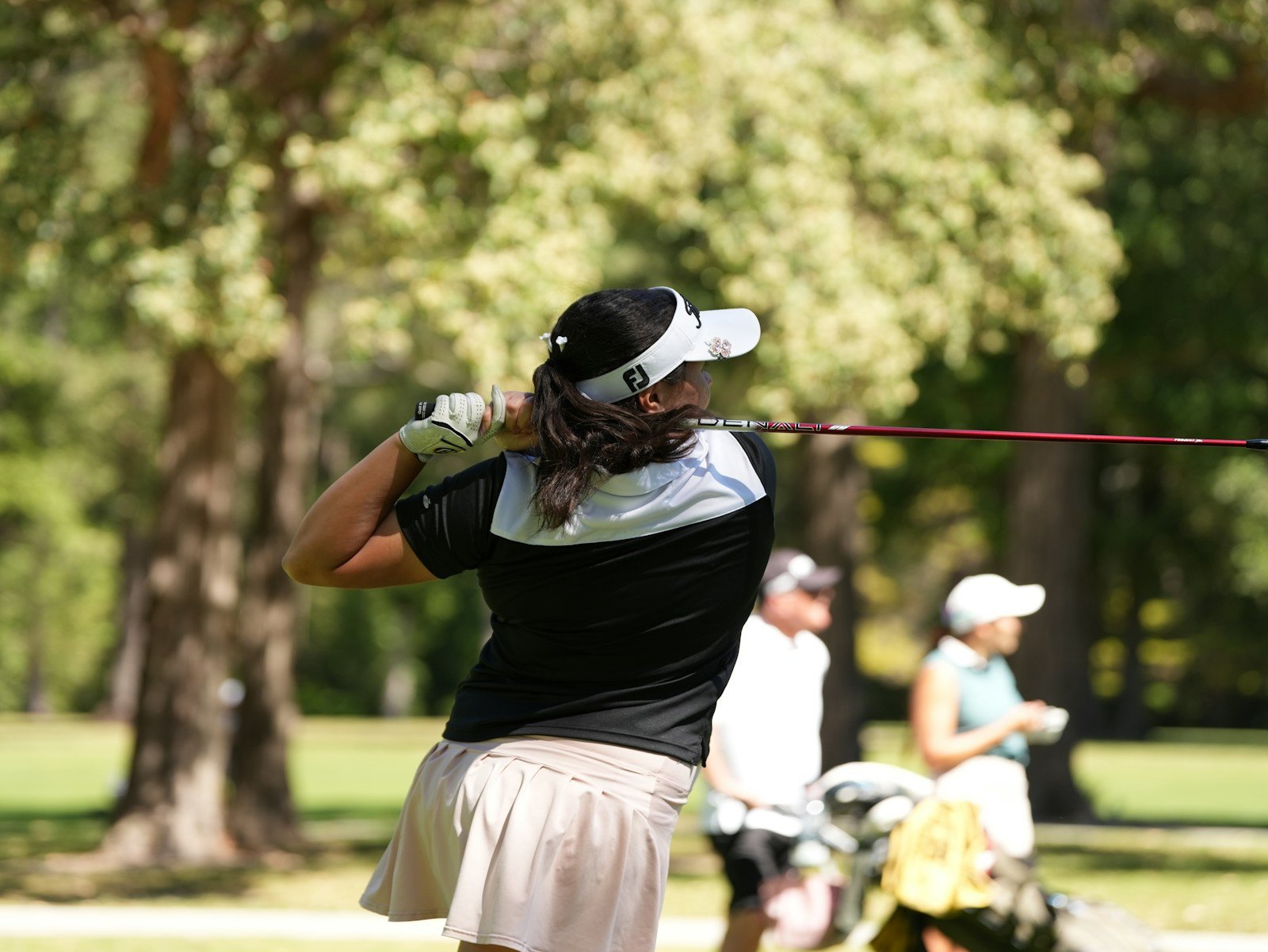 a golfer swinging one of her left-handed women's golf clubs on a sunny fairway