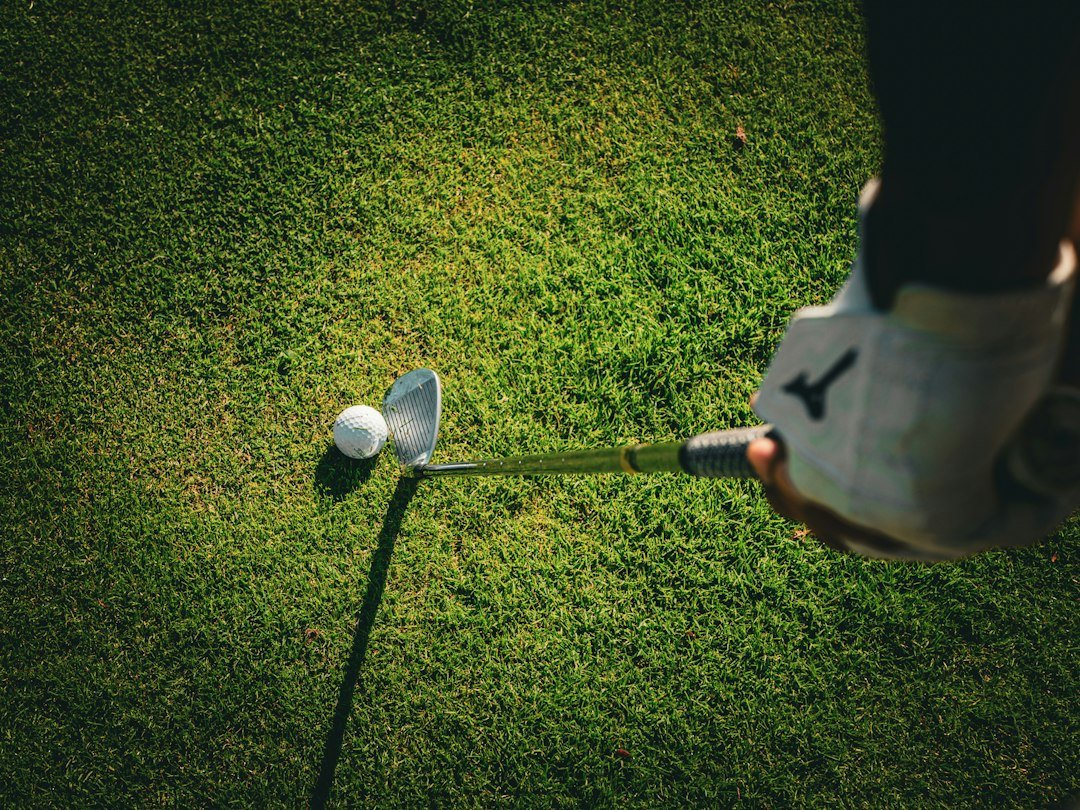 Golfer gripping a wedge at address, with the ball and clubface visible