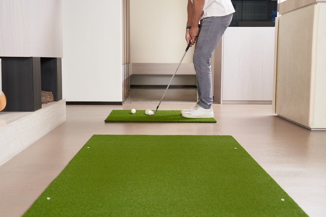 Golfer chipping on a home practice mat used with a golf simulator