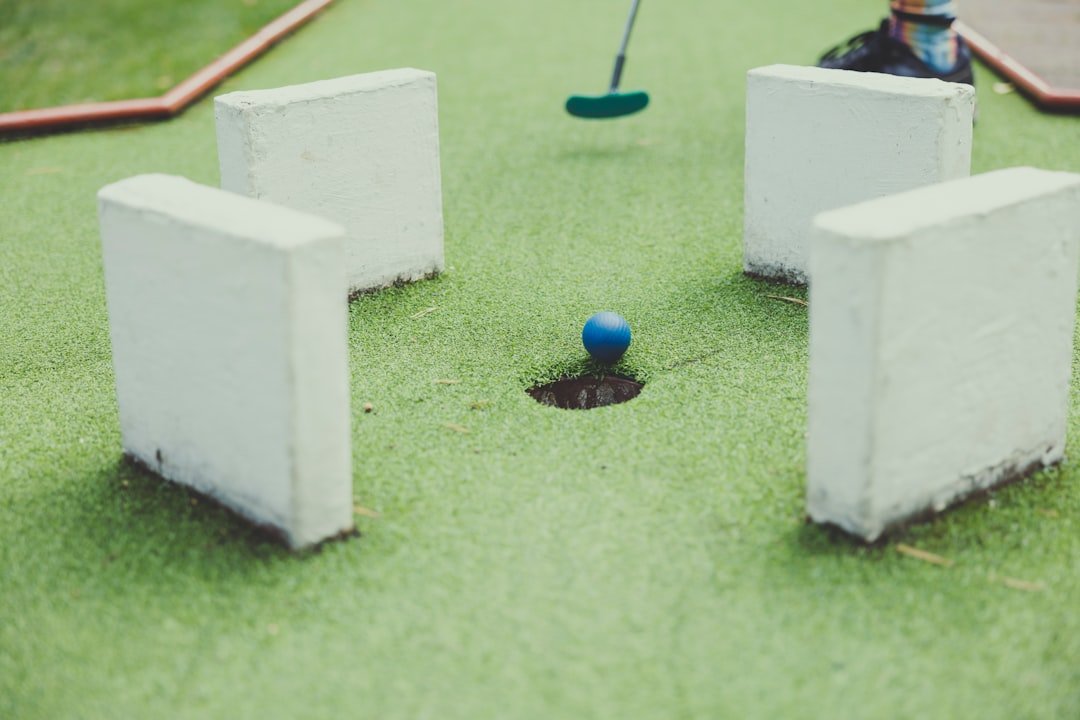 Mini golf ball rolling toward the hole between obstacle walls