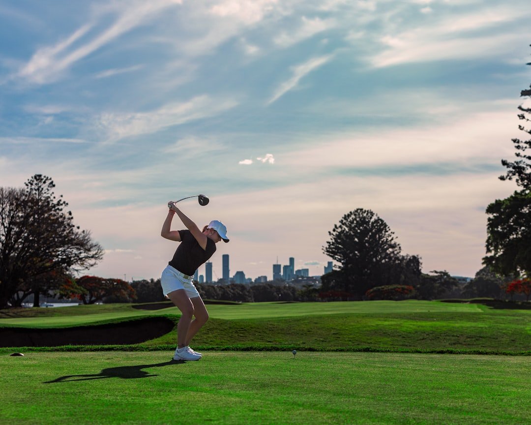 Golfer swinging a club on a golf course fairway