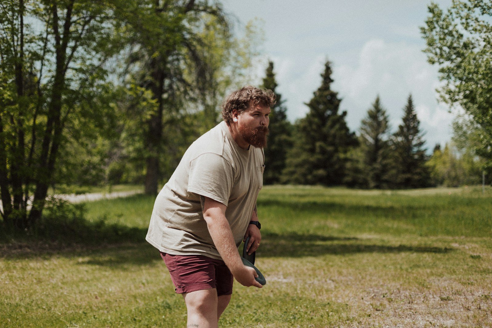Golfer in a low, bent-knee stance setting up for a sidearm disc golf throw