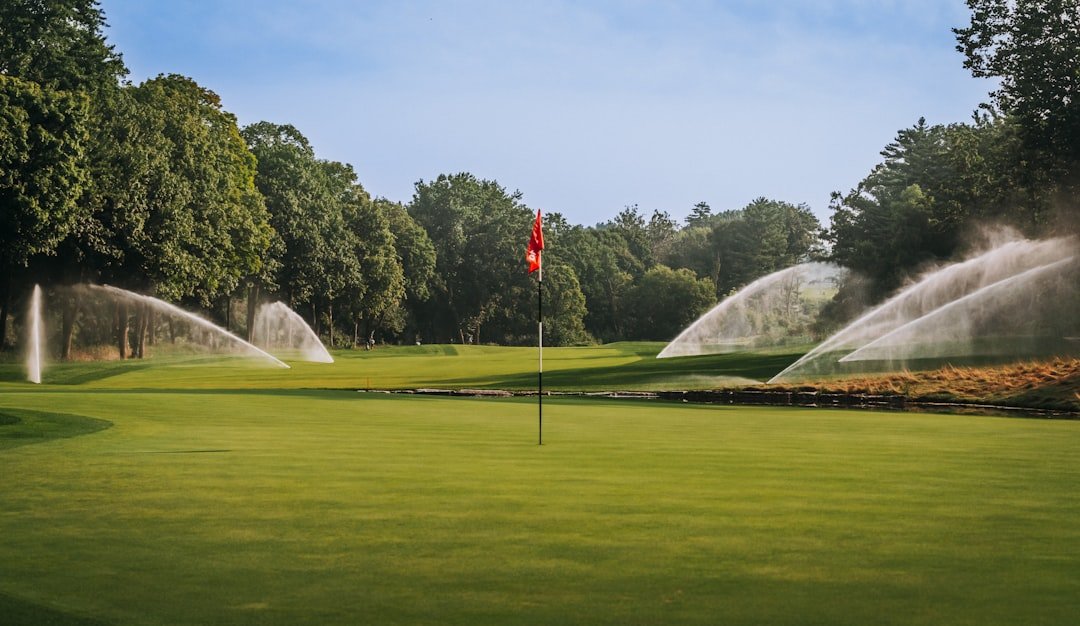 Sprinklers irrigating a golf course green, part of the ongoing cost to maintain a golf course