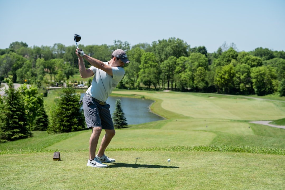 Golfer completing a full swing on the course, where fresh grooves help control spin
