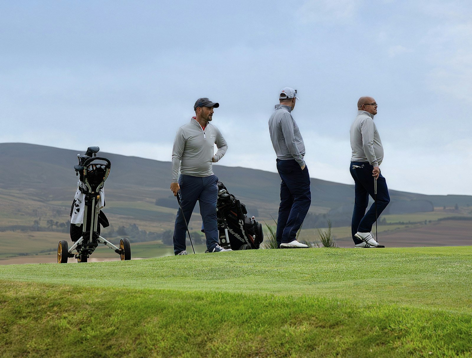 Three friends in golf attire on a course, a typical group for a casual round with a breakfast ball