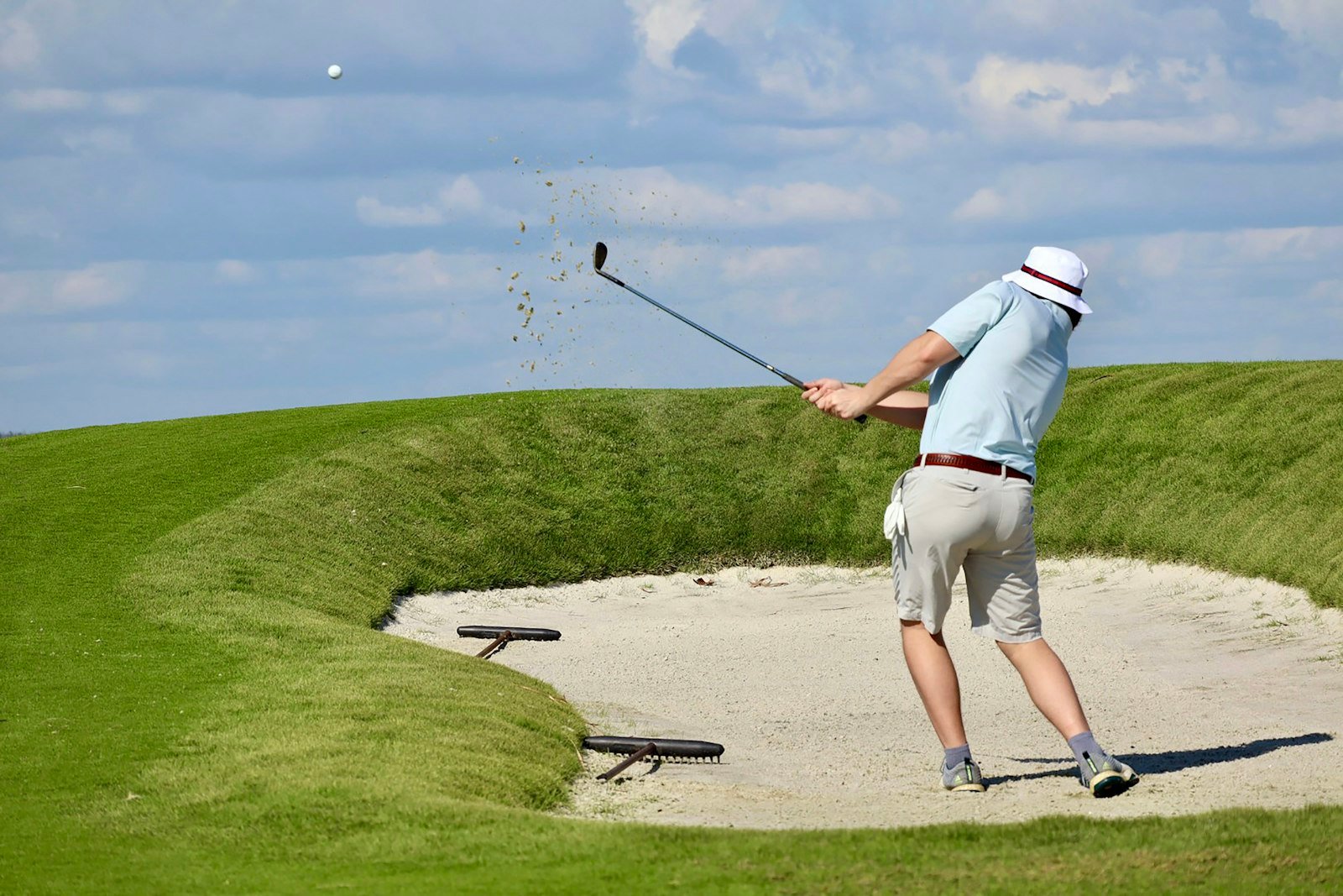 What is a sandie in golf? A golfer blasting a ball out of a greenside bunker