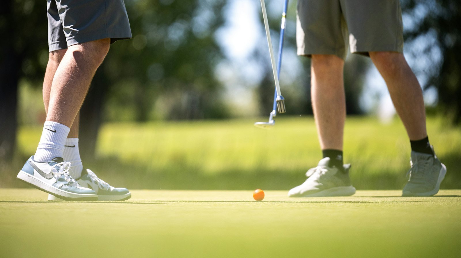 Can you wear jeans golfing at a casual course? Two golfers in shorts and sneakers on a green
