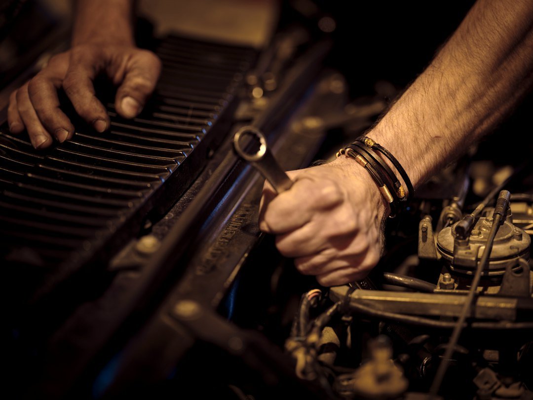 Hands using a wrench on a carbureted engine, similar to servicing a gas golf cart that jerks