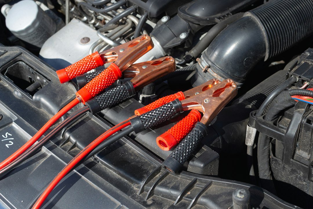 Jumper cable clamps in a car engine bay, the kind of quick hookup people try when they use car batteries in a golf cart