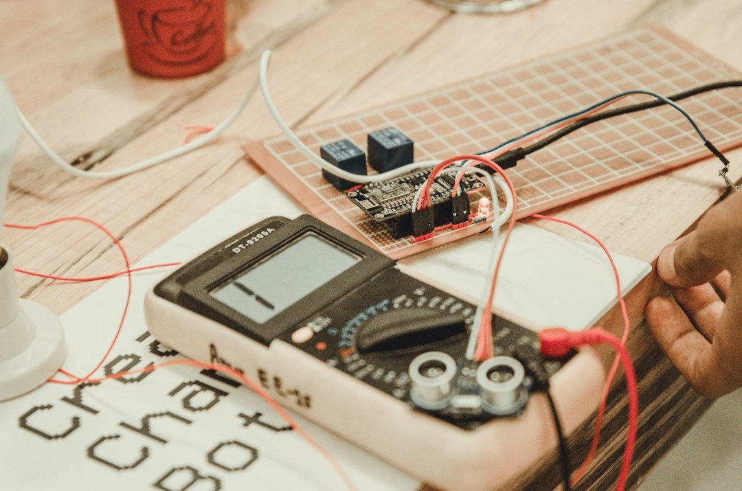 Digital multimeter with test leads on a workbench next to a small circuit board