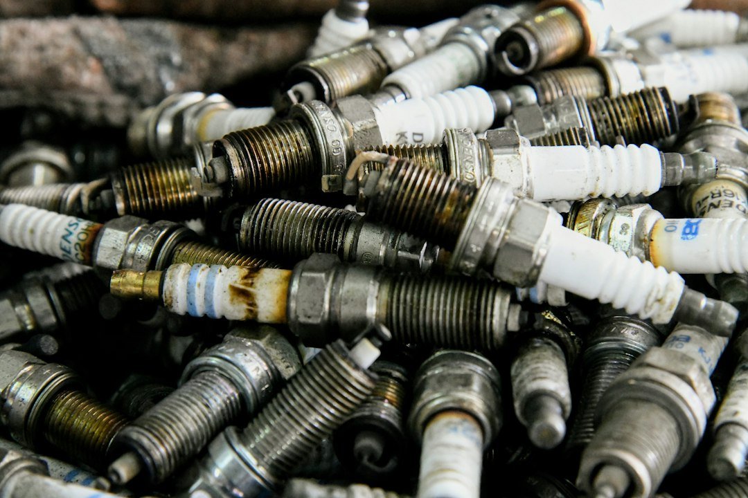 Pile of used spark plugs on a mechanic's bench, worn plugs are a common backfire cause